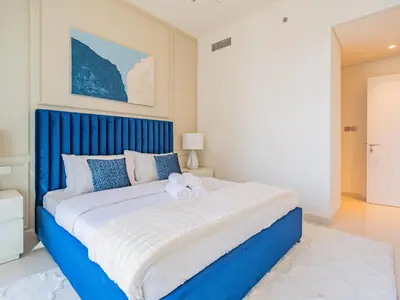 a bedroom with a large bed with a blue headboard at Exceptional 2BR-Private Beach Access-Palm Jumeirah in Dubai