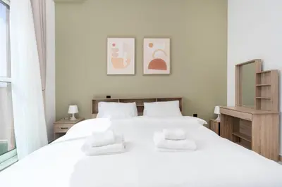 a bedroom with a white bed with two towels on it at Central 1bdr - Al Quoz - Al Khail Height in Dubai