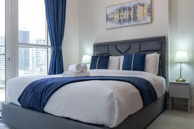 a bedroom with a large bed with blue curtains and a window at Dunya Tower Luxury and 2 min walk to Dubai Mall and Burj Khalifa in heart of Downtown in Dubai