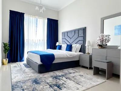 a bedroom with a large bed and blue curtains at Dunya Tower Luxury and 2 min walk to Dubai Mall and Burj Khalifa in heart of Downtown in Dubai