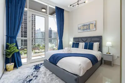 a bedroom with a large bed with blue curtains and a window at Dunya Tower Luxury and 2 min walk to Dubai Mall and Burj Khalifa in heart of Downtown in Dubai