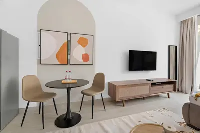 a living room with a table and chairs and a tv at Silkhaus new studio in JVC with queen Bed in Dubai