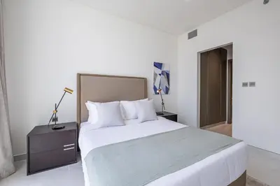 a white bedroom with a large bed with white pillows at Fully Furnished I Lagoons View I District One in Dubai