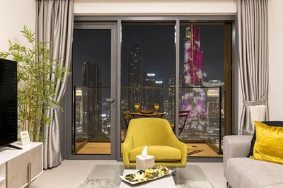 a living room with a yellow chair and a large window at SmartStay at Burj Royale - Full Burj Khalifa View - Brand New Luxury Apartments in Dubai