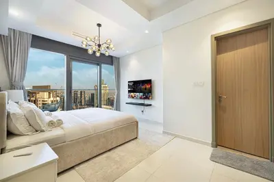 a bedroom with a large bed and a large window at Luxe 2BR with Burj Khalifa View & Infinity Pool in Dubai