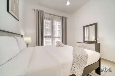 a white bedroom with a large white bed and a window at Soothing 1BR at Safi 1B Town Square Dubailand by Deluxe Holiday Homes in Dubai