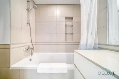 a white bathroom with a tub and a shower at Soothing 1BR at Safi 1B Town Square Dubailand by Deluxe Holiday Homes in Dubai