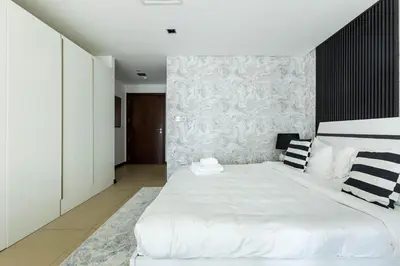 a bedroom with a large white bed and a wall at Nasma Luxury Stays - White Haven Studio With Charming Cityscape Views in Dubai