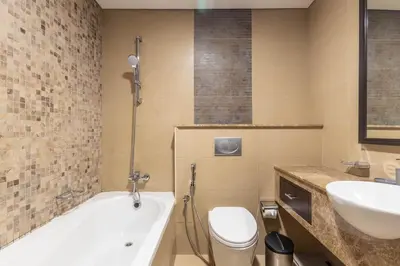 a bathroom with a tub and a toilet and a sink at Nasma Luxury Stays - White Haven Studio With Charming Cityscape Views in Dubai