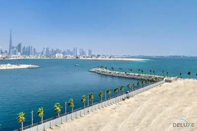 a beach with palm trees and a city in the background at Luxurious 4BR Penthouse with Assistant Room and a Sweeping Balcony Showcasing Burj Khalifa and Sea Views, Le Pont, La Mer by Deluxe Holiday Homes in Dubai