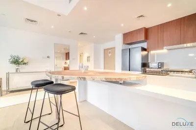 a kitchen with a island with two stools at Luxurious 4BR Penthouse with Assistant Room and a Sweeping Balcony Showcasing Burj Khalifa and Sea Views, Le Pont, La Mer by Deluxe Holiday Homes in Dubai