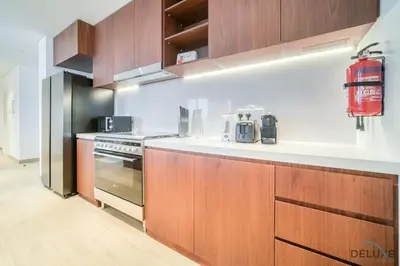 a kitchen with wooden cabinets and a stove top oven at Luxurious 4BR Penthouse with Assistant Room and a Sweeping Balcony Showcasing Burj Khalifa and Sea Views, Le Pont, La Mer by Deluxe Holiday Homes in Dubai
