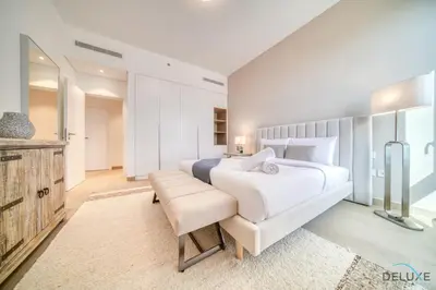 a bedroom with a large white bed and a bench at Luxurious 4BR Penthouse with Assistant Room and a Sweeping Balcony Showcasing Burj Khalifa and Sea Views, Le Pont, La Mer by Deluxe Holiday Homes in Dubai
