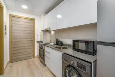 a kitchen with a washer and a sink and a dishwasher at Studio in JVC - Heart of Dubaï - Bloom Height in Dubai