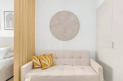 a living room with a white couch with yellow pillows at Studio in JVC - Heart of Dubaï - Bloom Height in Dubai