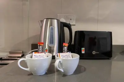 two coffee cups sitting on a counter next to a toaster at Studio in JVC - Heart of Dubaï - Bloom Height in Dubai