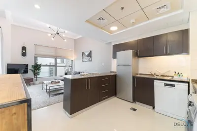 a kitchen with brown cabinets and a white refrigerator at Scenic 1BR at Bay Central 1 Dubai Marina by Deluxe Holiday Homes in Dubai