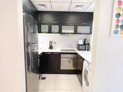 a kitchen with black cabinets and a refrigerator at RH- City Living in Style, Large 1 BR with open Terrace, Dubai Marina in Dubai