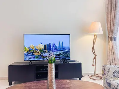 a living room with a tv and a vase with flowers at RH- City Living in Style, Large 1 BR with open Terrace, Dubai Marina in Dubai