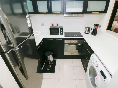a small kitchen with a refrigerator and a microwave at RH- City Living in Style, Large 1 BR with open Terrace, Dubai Marina in Dubai