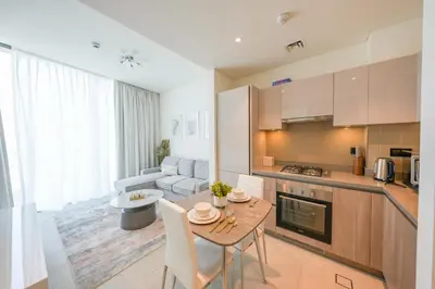 a kitchen and living room with a table and chairs at Bright Apartment With Panoramic CityScape Views in Dubai