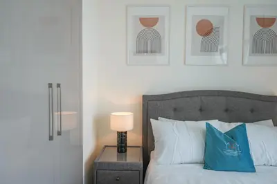 a bedroom with a bed with a lamp and pictures on the wall at Bright Apartment With Panoramic CityScape Views in Dubai