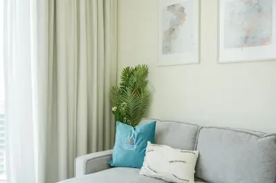 a living room with a gray couch with a blue pillow at Bright Apartment With Panoramic CityScape Views in Dubai