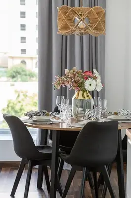 a wooden table with chairs and a vase of flowers at Frank Porter - Bonaire Tower in Dubai