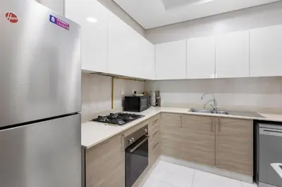 a kitchen with white cabinets and a stainless steel refrigerator at Spacious 1 bedroom in Business Bay - Close to Downtown in Dubai