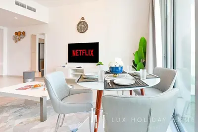 a dining room with a table and chairs and a tv at LUX The Dubai Creek View Suite in Dubai