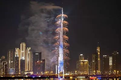 a tall building with fireworks in a city at night at LUX The Dubai Creek View Suite in Dubai