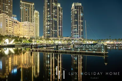 a city skyline with a marina at night at LUX The Dubai Creek View Suite in Dubai