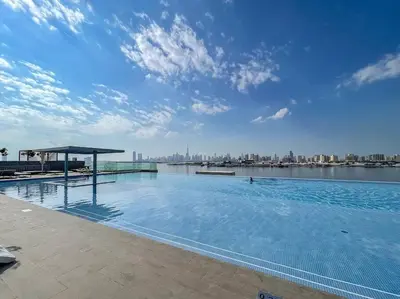 a large swimming pool with a view of a city at 2bdr Emaar The Grand - Sea View - Creek Harboor in Dubai