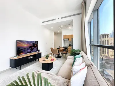 a living room with a couch and a tv at Trophy - Downtown Skyline Sanctuary Suite in Dubai