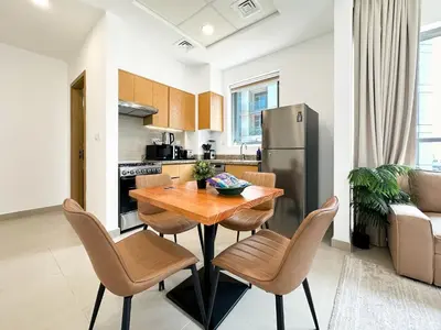 a kitchen and dining room with a wooden table and chairs at Trophy - Downtown Skyline Sanctuary Suite in Dubai