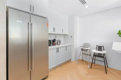 a kitchen with white cabinets and a stainless steel refrigerator at Private villa in Dubai with swimming pool and huge garden in Dubai
