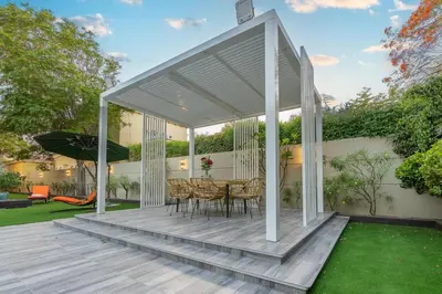 a white pergola on a deck with a table and chairs at Private villa in Dubai with swimming pool and huge garden in Dubai