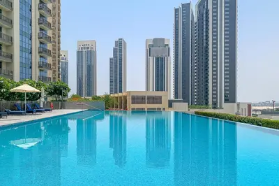 a large blue swimming pool with tall buildings in the background at Frank Porter - Creekside 18 in Dubai