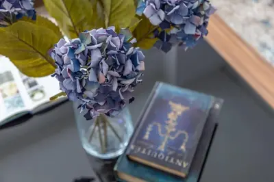 a vase with purple flowers and a book on a table at Frank Porter - Beauport in Dubai