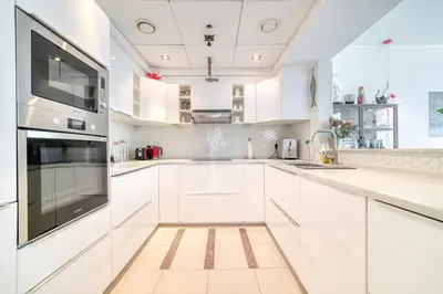 a white kitchen with white cabinets and a large window at Fairfield Tower, Park Island, Dubai Marina - Mint Stay in Dubai