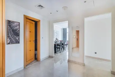 a hallway with white walls and a wooden door at The Smart Concierge - Marinascape Oceanic in Dubai