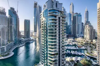a tall building next to a river in a city at The Smart Concierge - Marinascape Oceanic in Dubai