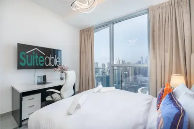 a hotel room with a bed and a desk and a window at Luxurious 3BR Apartment with Panoramic Marina View in Dubai