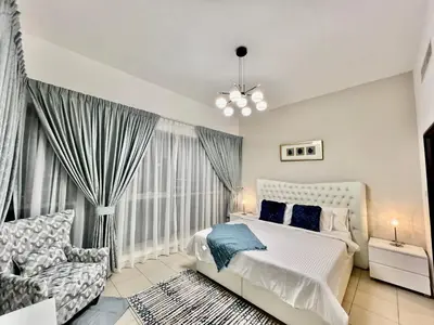 a bedroom with a bed and a chair and a window at INA Homes-BLVD Central 2BHK Apartment near Burj Khalifa in Dubai