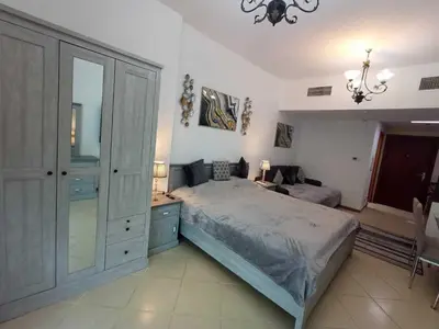 a bedroom with a bed and a desk and a chandelier at Diamond 2 Tower Marina Apartment in Dubai