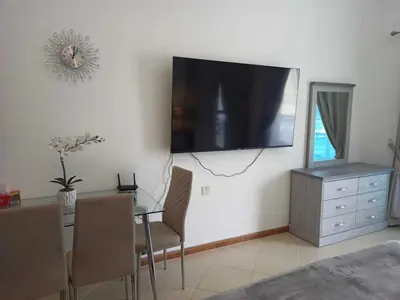 a living room with a table and a television on a wall at Diamond 2 Tower Marina Apartment in Dubai