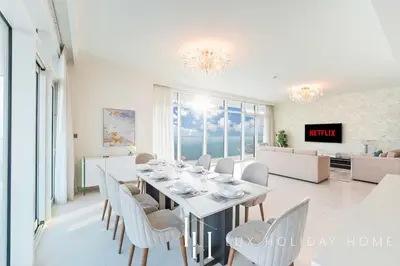 a white dining room with a long table and chairs at LUX The Ultimate Palm Sea Skyline Penthouse in Dubai