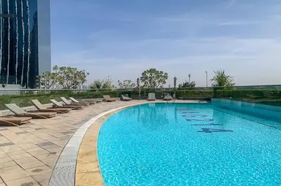 a large swimming pool with lounge chairs next to a building at Frank Porter - MAG214 in Dubai