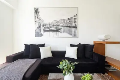 a living room with a black couch and a painting at Frank Porter - MAG214 in Dubai