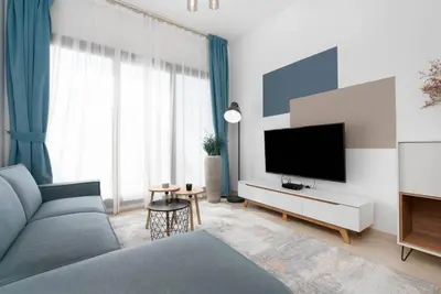 a living room with a couch and a flat screen tv at Nice 1Bedroom - UNA Townsquare in Dubai